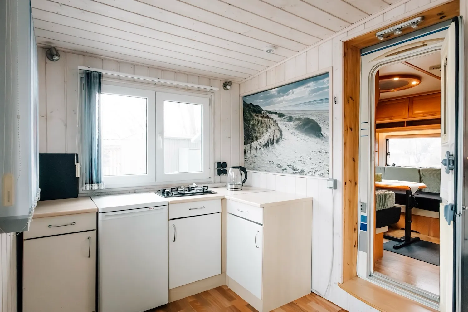 Küche im festen Anbau der Camping-Suite Karl Albrecht – weiße Einbauküche mit Fenster, hell und modern eingerichtet - Kaiser Campingplatz in Bad Feilnbach