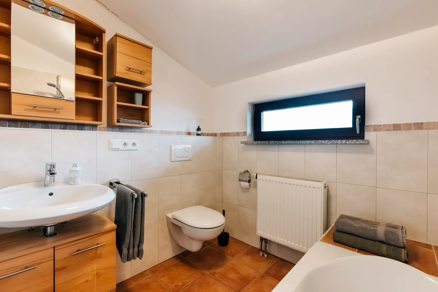 Badezimmer der Ferienwohnung König Ludwig mit Badewanne, WC, Waschbecken und klassischen Fliesen in Terrakotta und Weiß - Kaiser Campingplatz in Bad Feilnbach